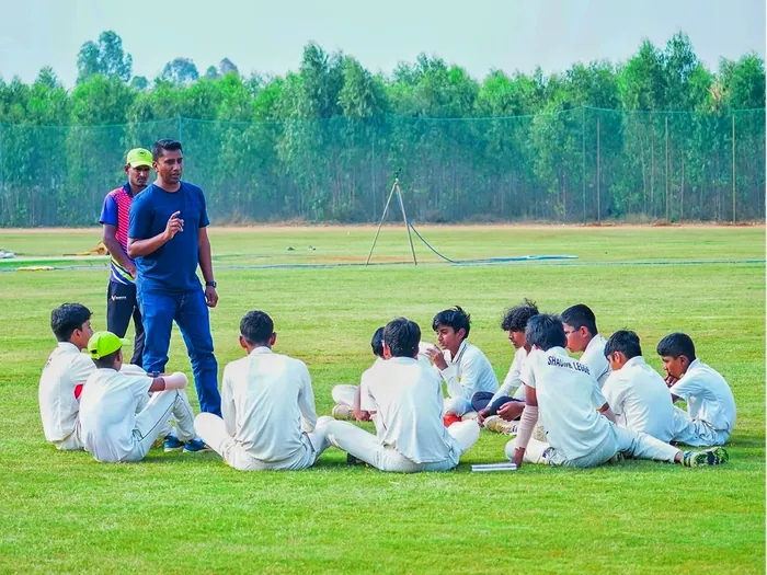 A coach briefing a group of young players on the outfield